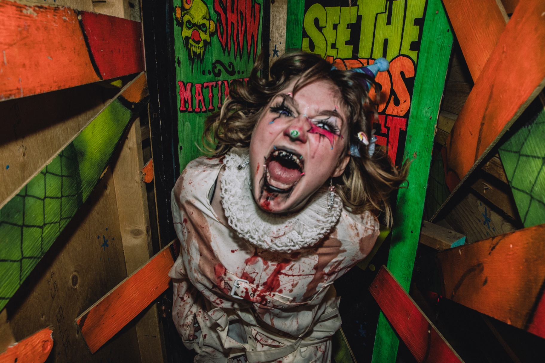 Costumed scare actor screaming at a guest inside a ScreamFest haunted house